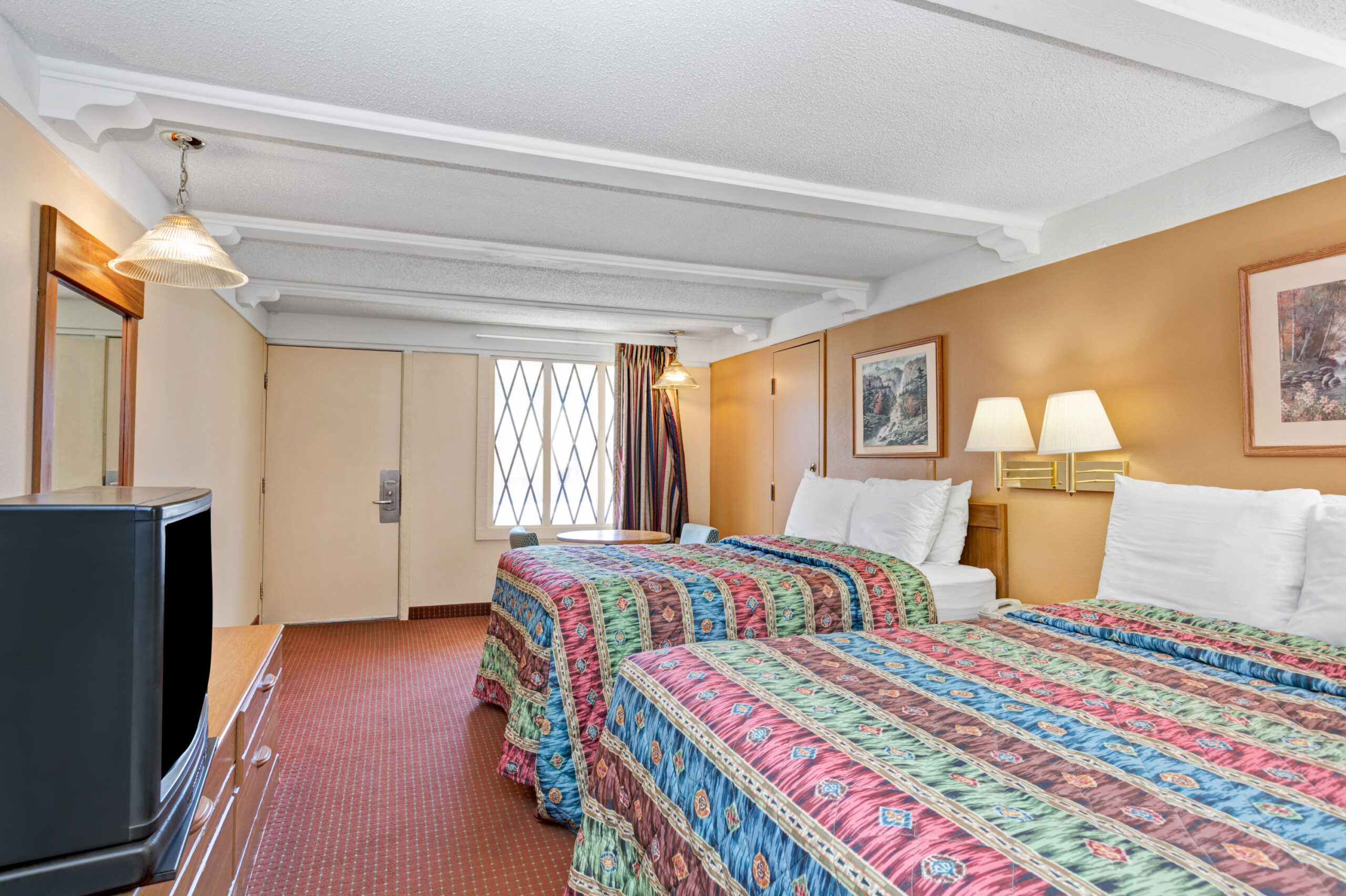 Hotel room with two double beds and colorful bedding.