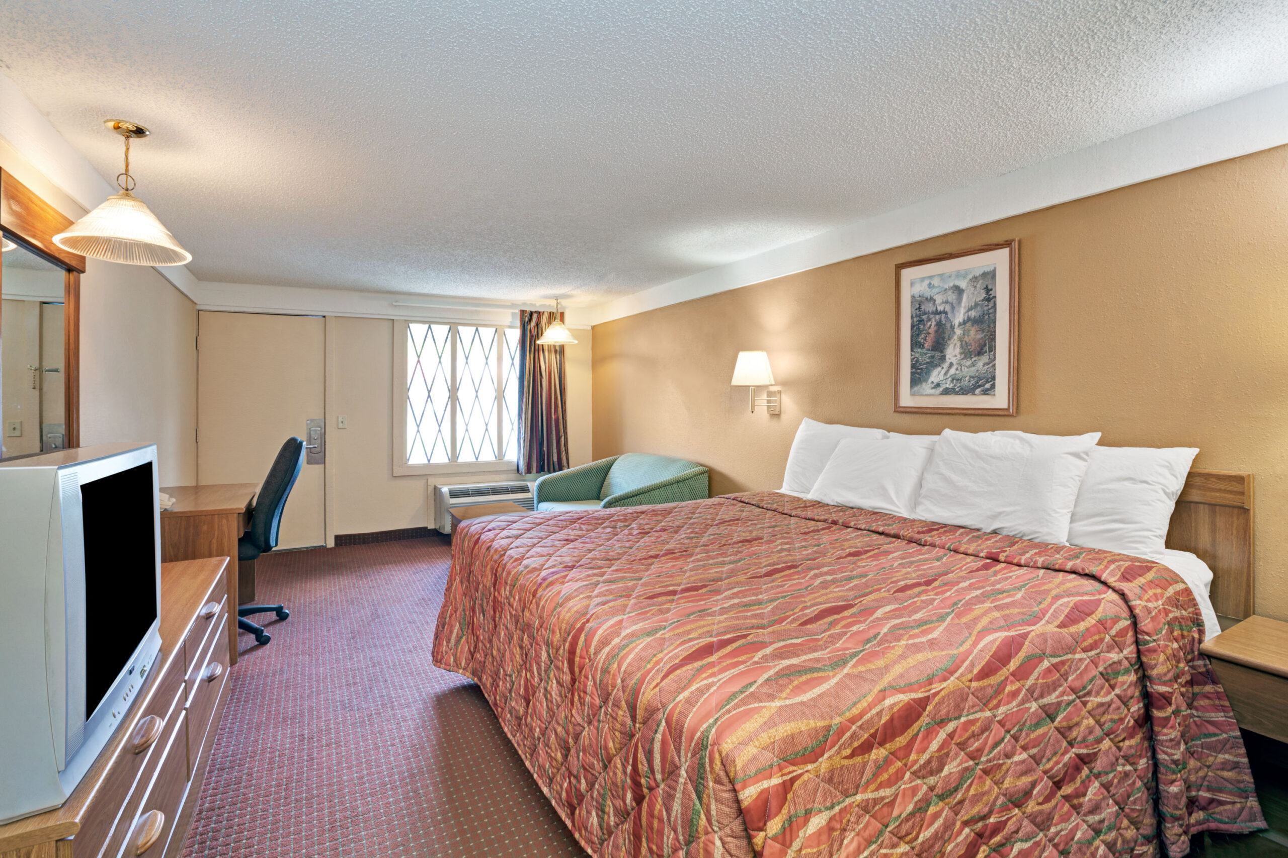Spacious hotel room with king bed and desk.