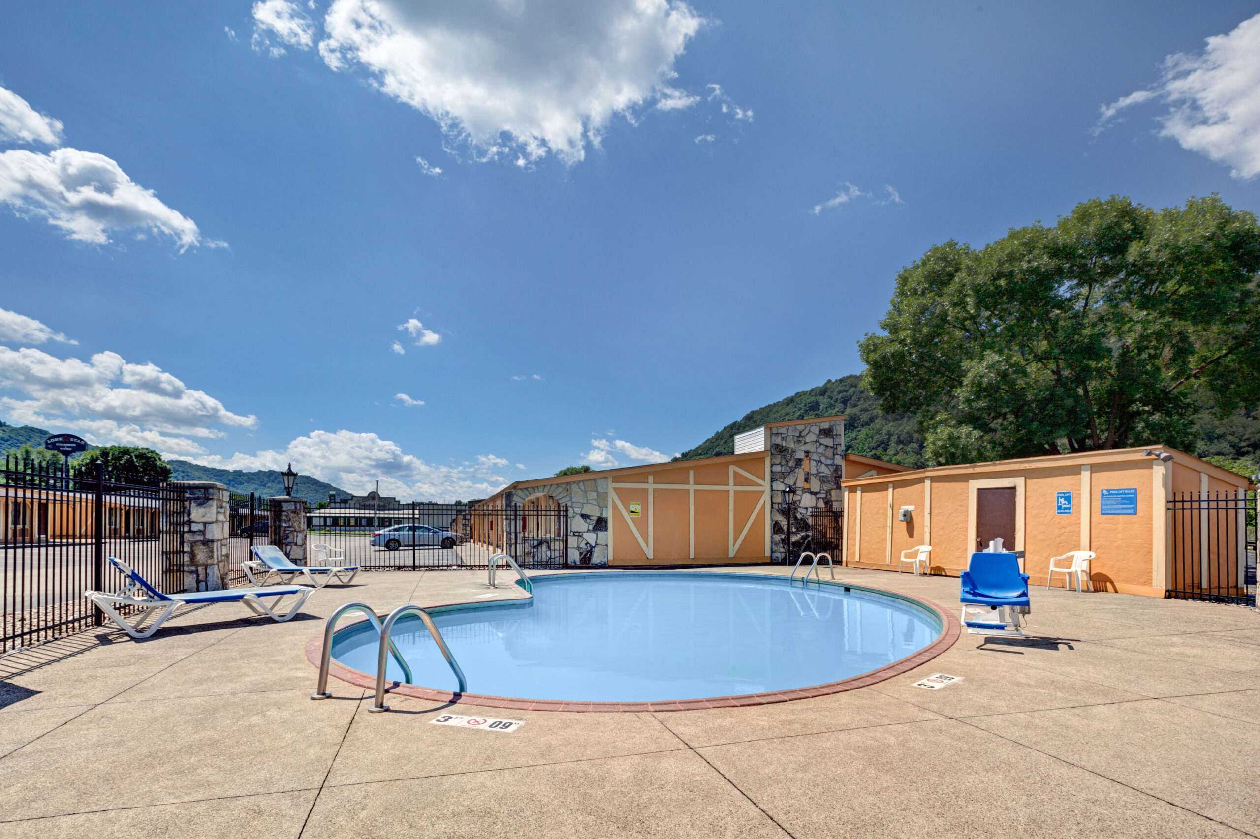 Outdoor swimming pool with lounge chairs and trees.