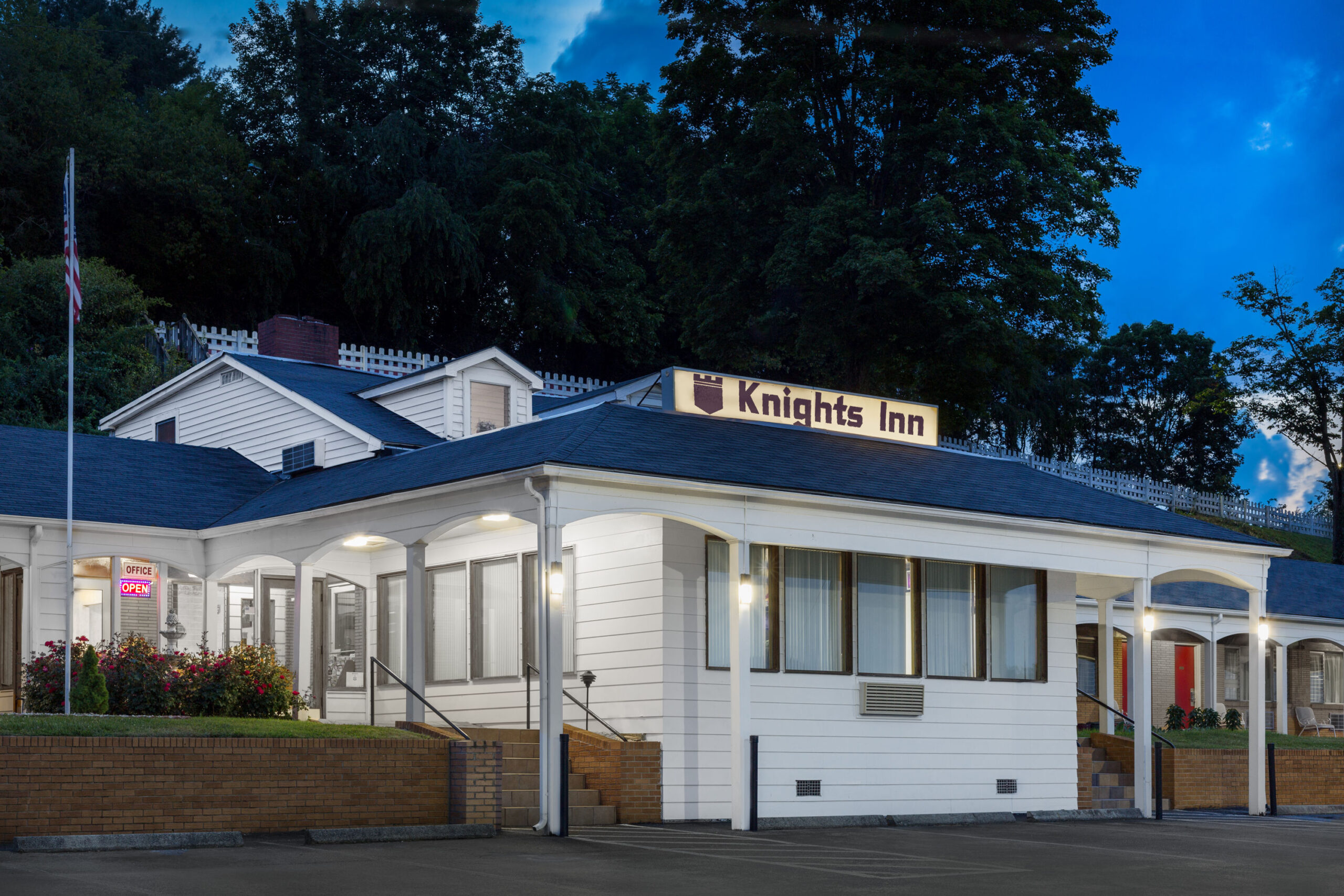 Knights Inn hotel exterior with flag and landscaping at night.
