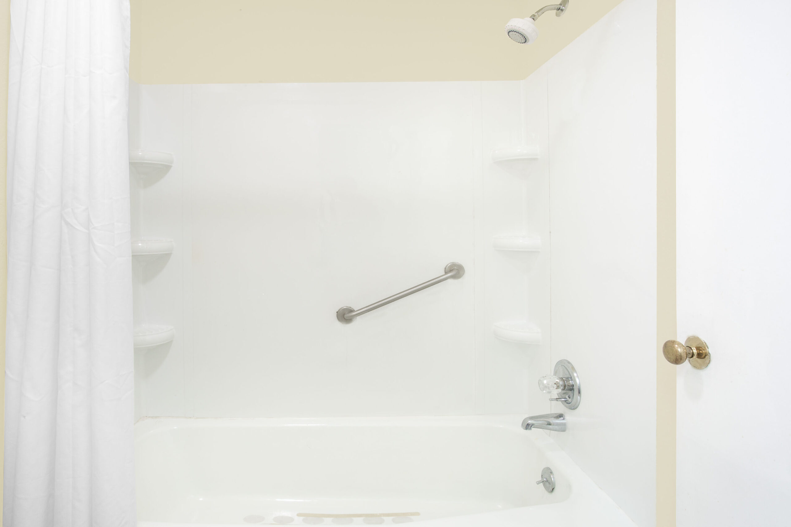 Clean white bathtub with shower and grab bar.