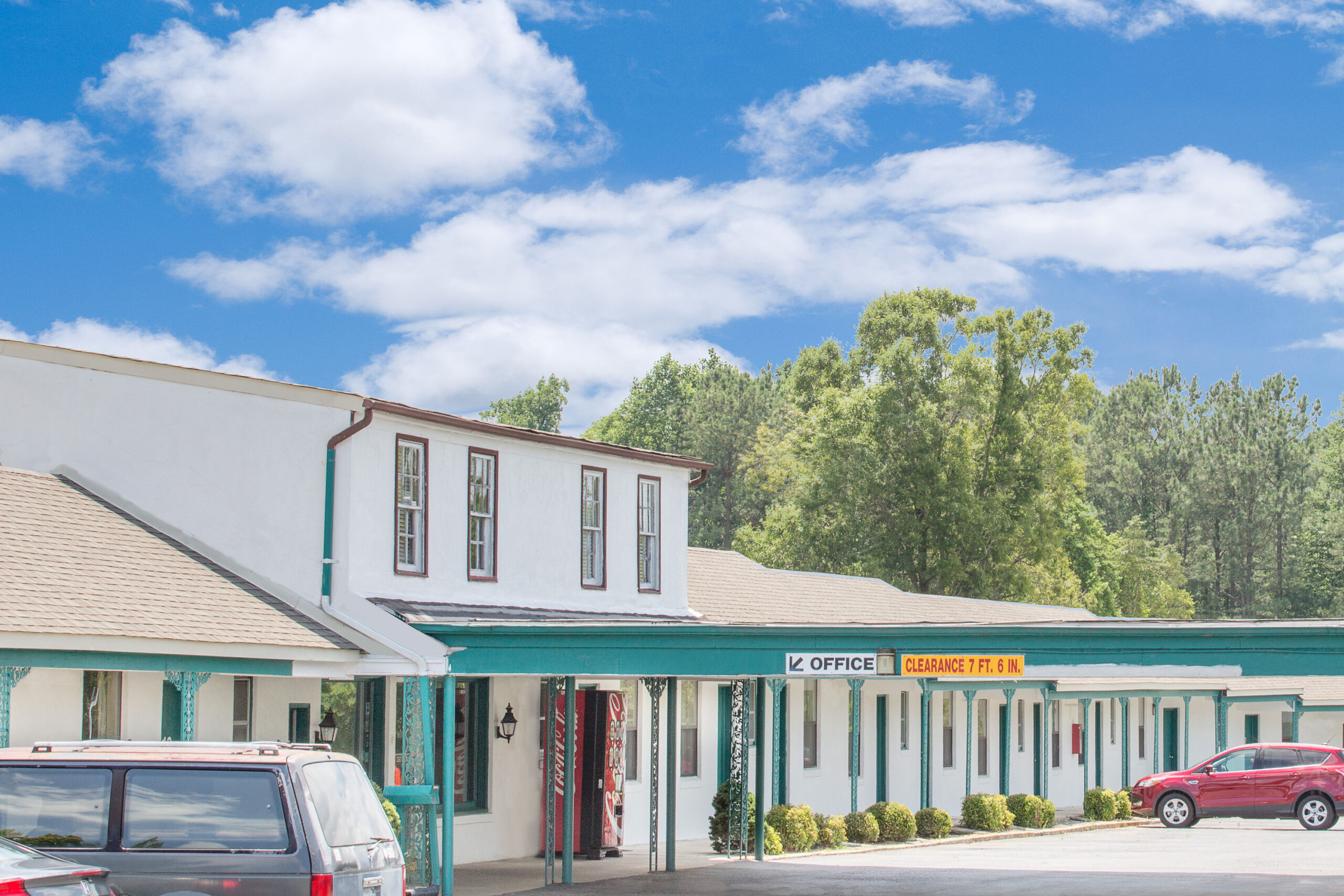 Motel exterior with parking and trees in the background.