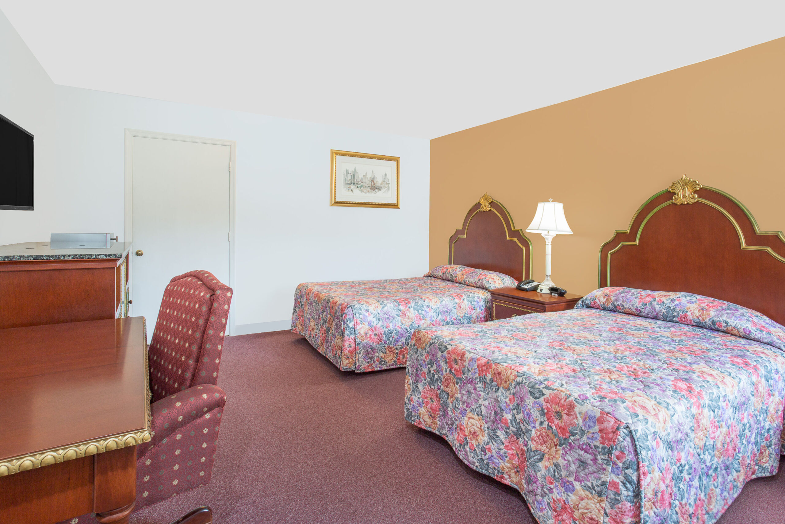 Hotel room with two beds, desk, and TV.