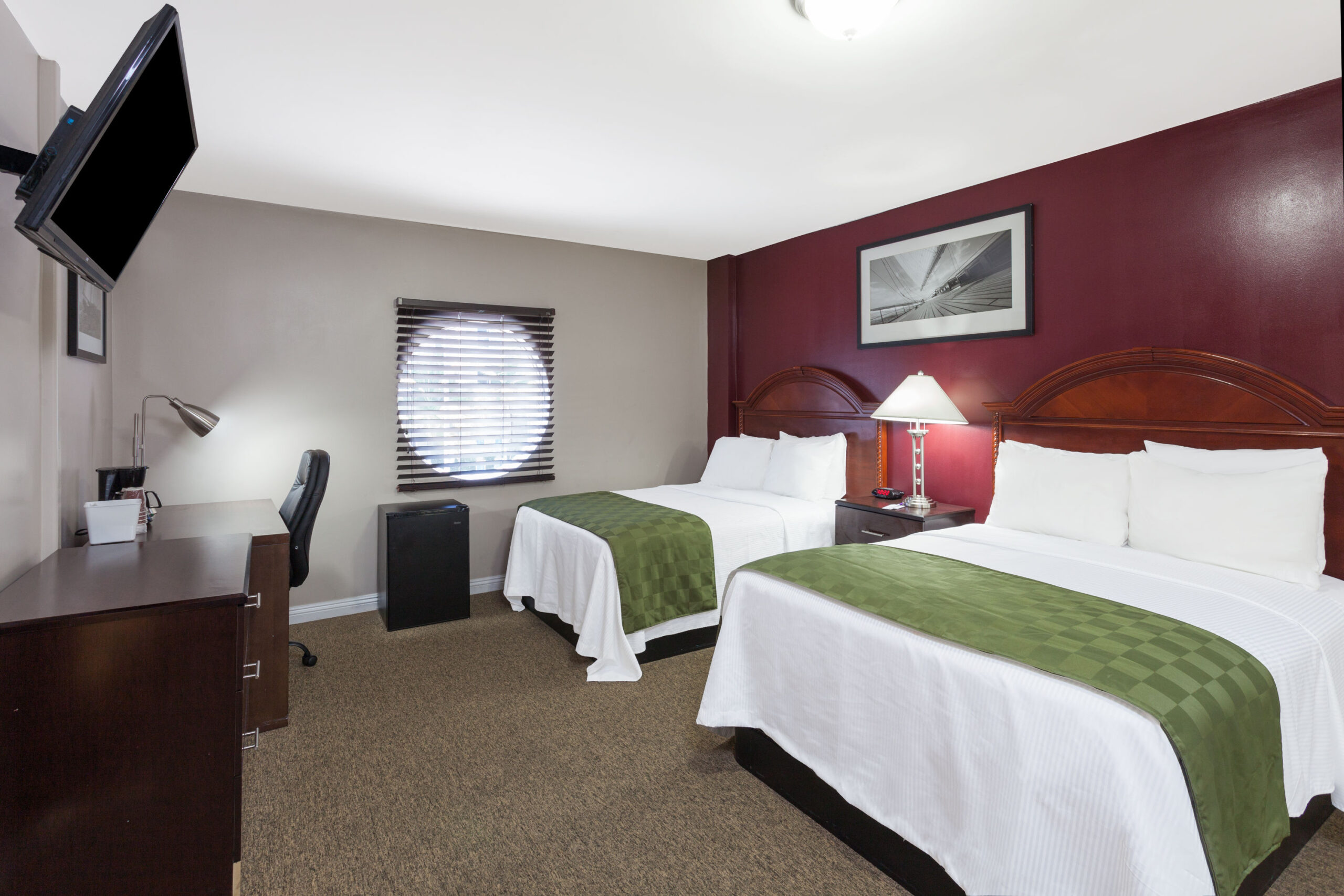 Hotel room with two double beds and a work area.