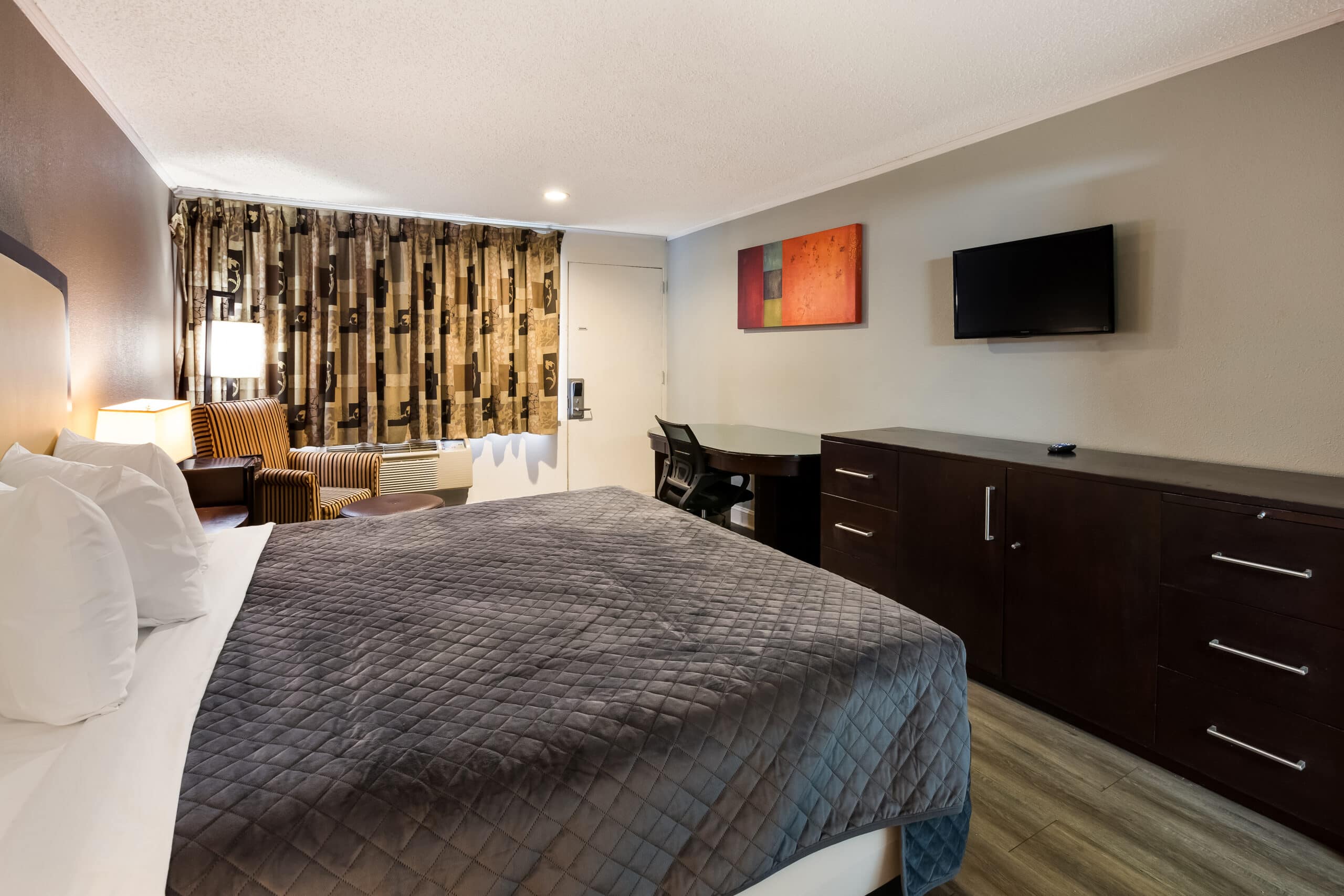 Hotel room with a king bed and a seating area.