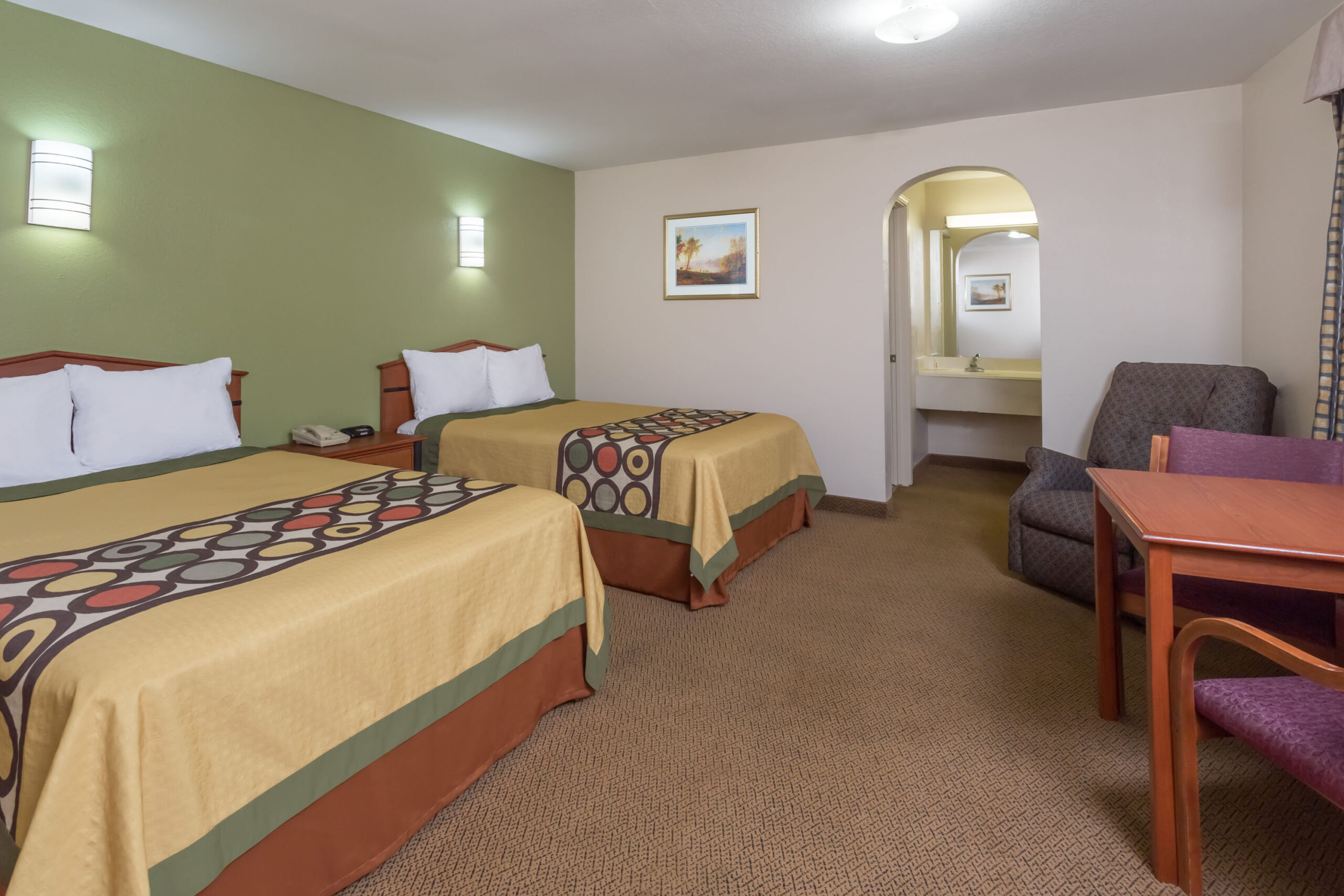 Hotel room with two beds and a work area.