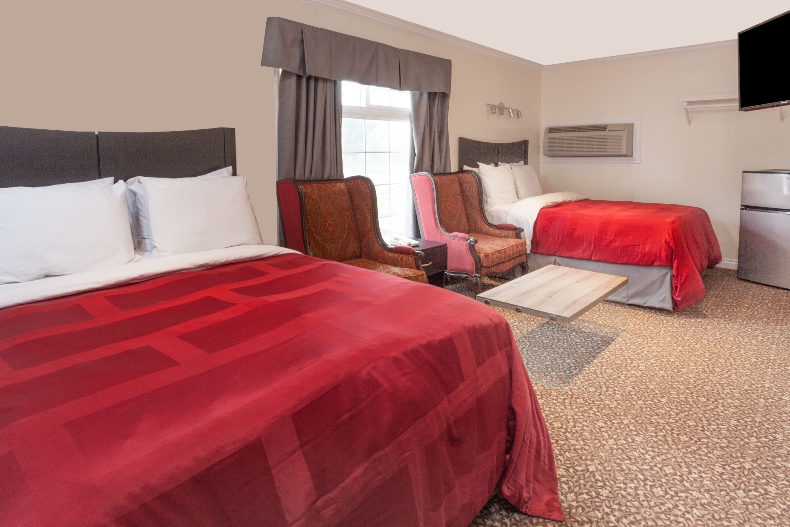 Two beds with red bedding.