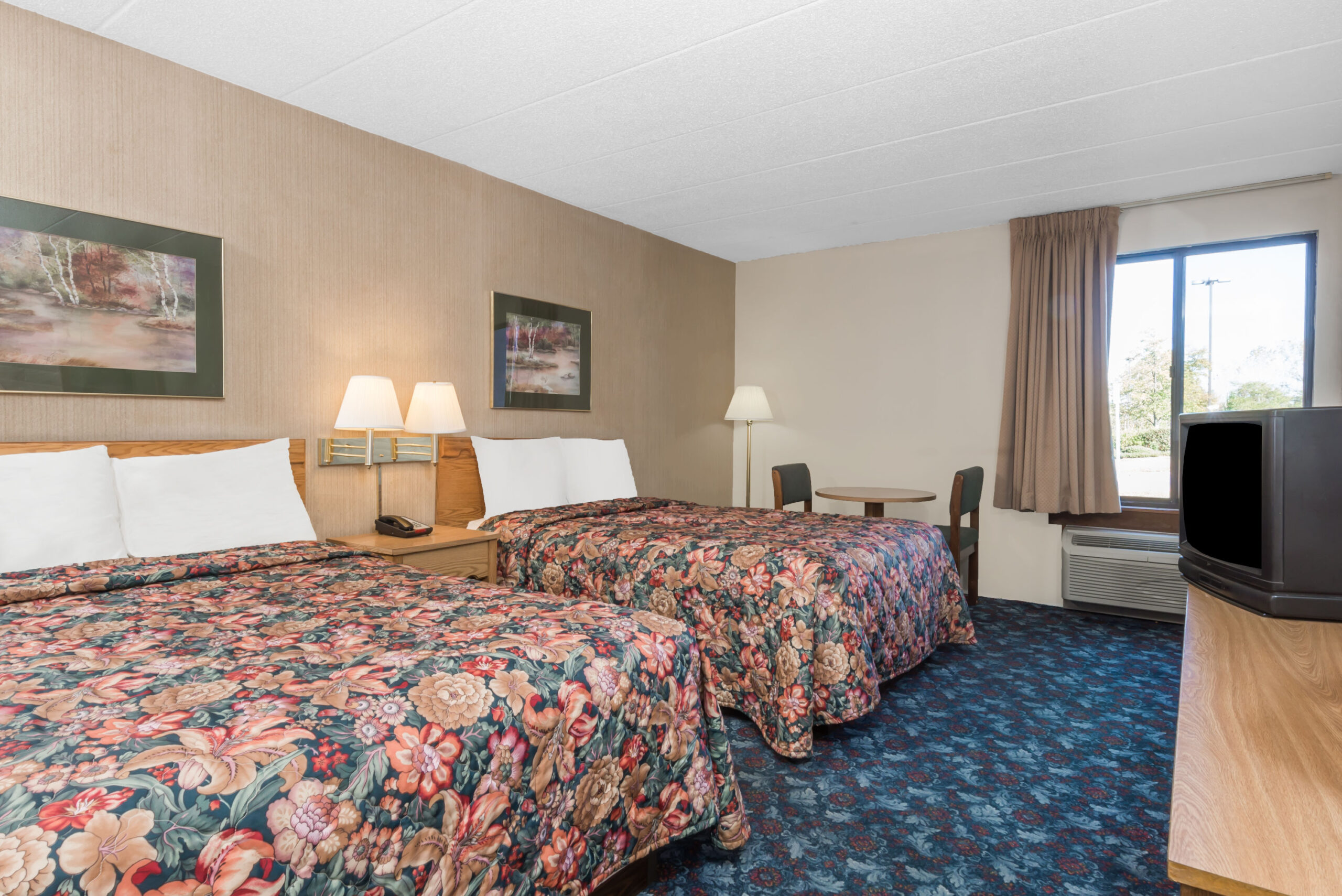 Hotel room with two double beds with a seating area.