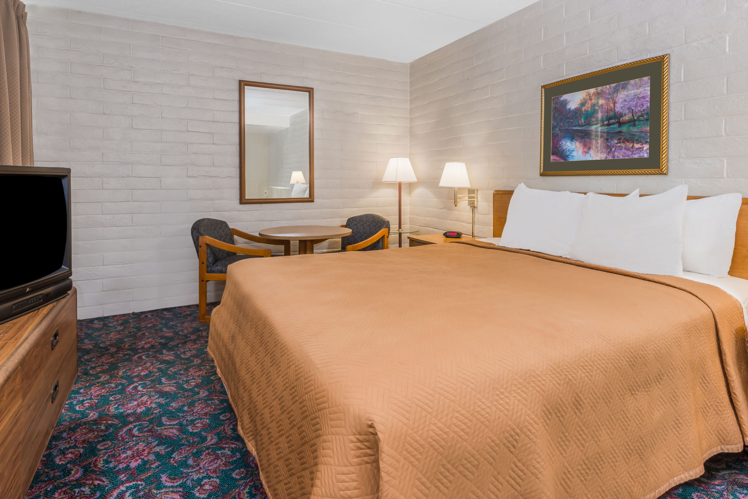 Hotel room with a king bed and a seating area.