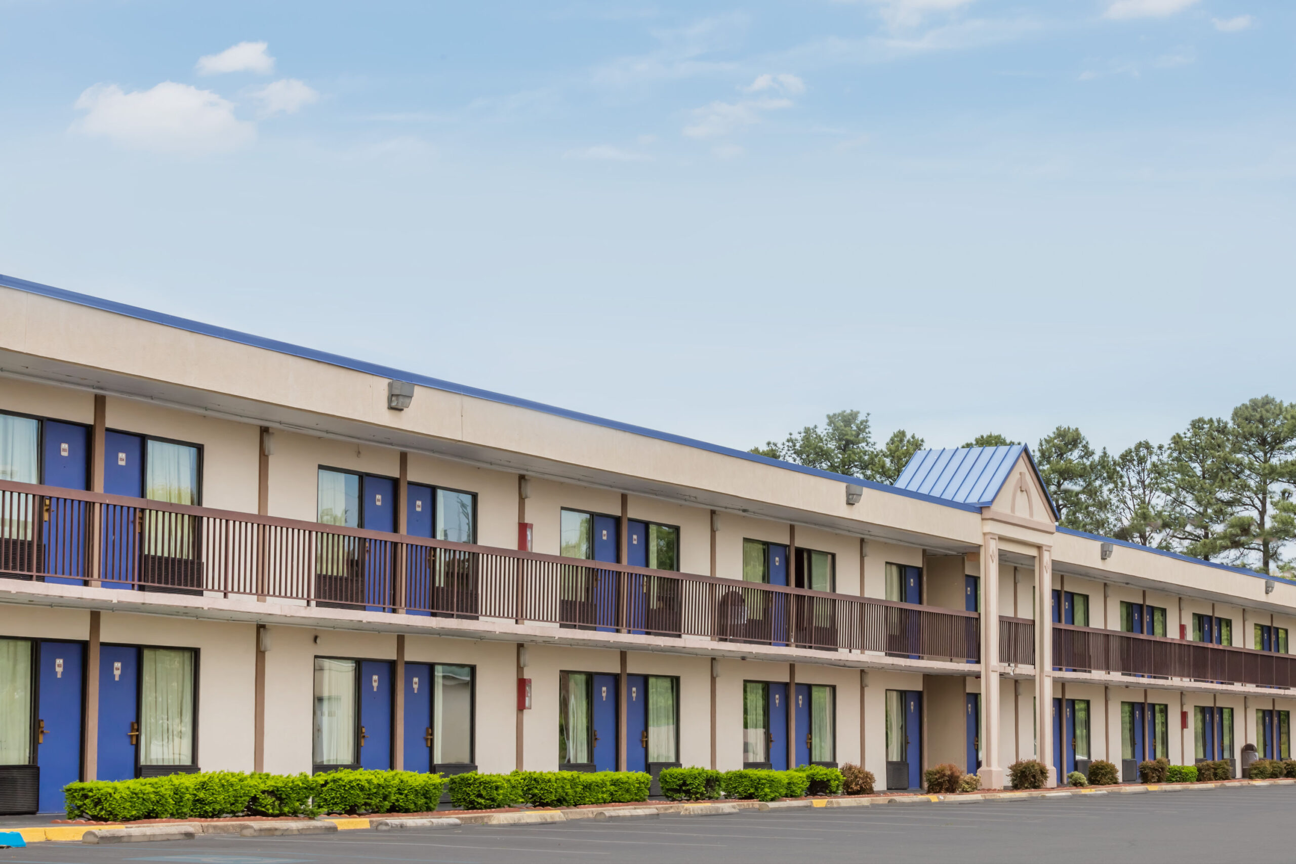 Two-story motel exterior with balcony in daylight.