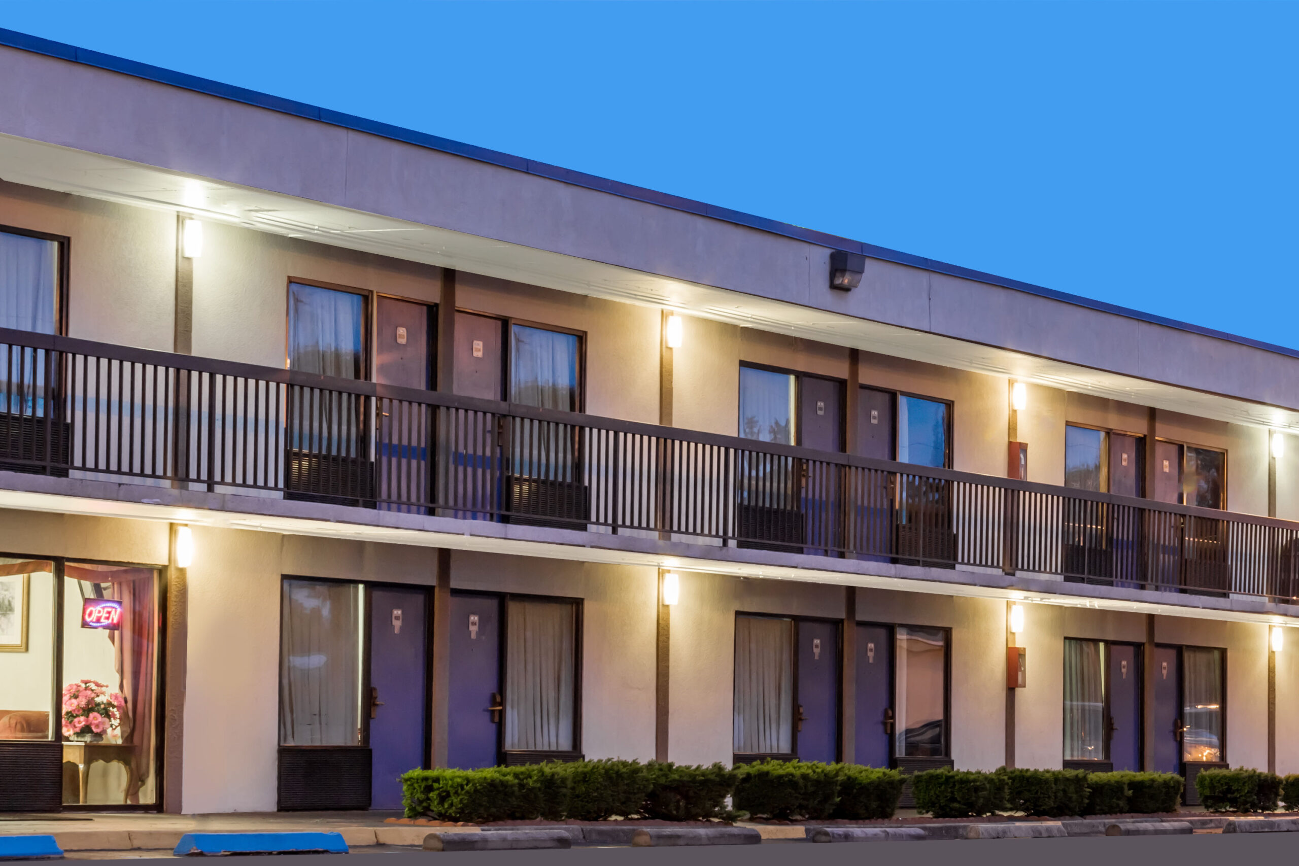 Two-story motel exterior with balcony and night lighting.