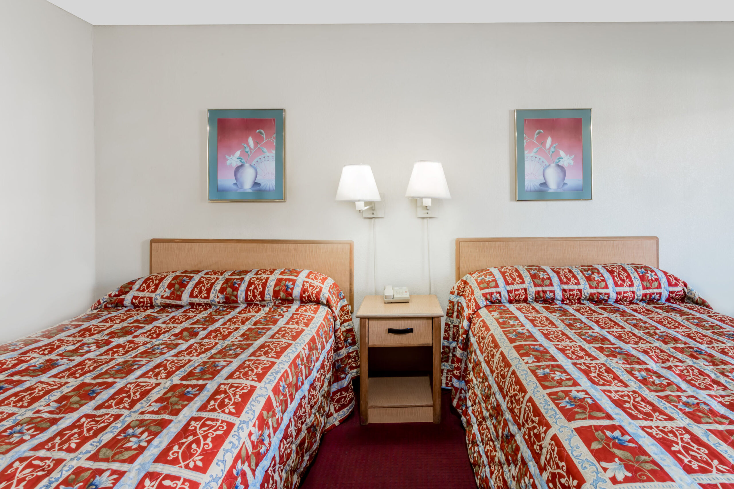 Hotel room with two double beds and wall lamps.