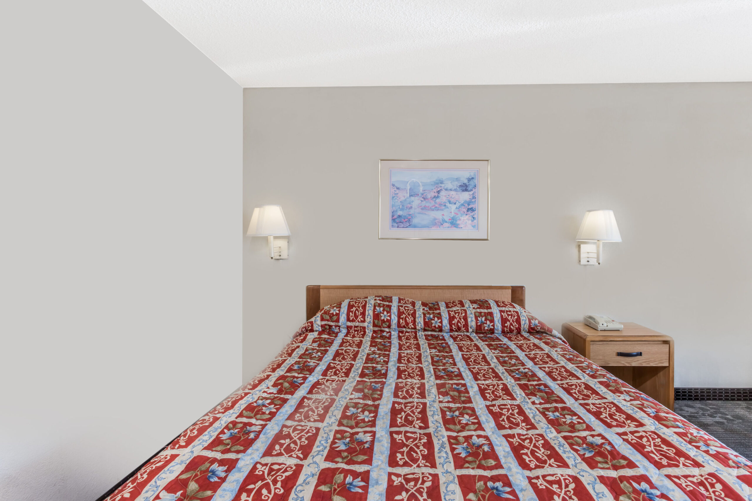 Single bed with patterned red quilt.