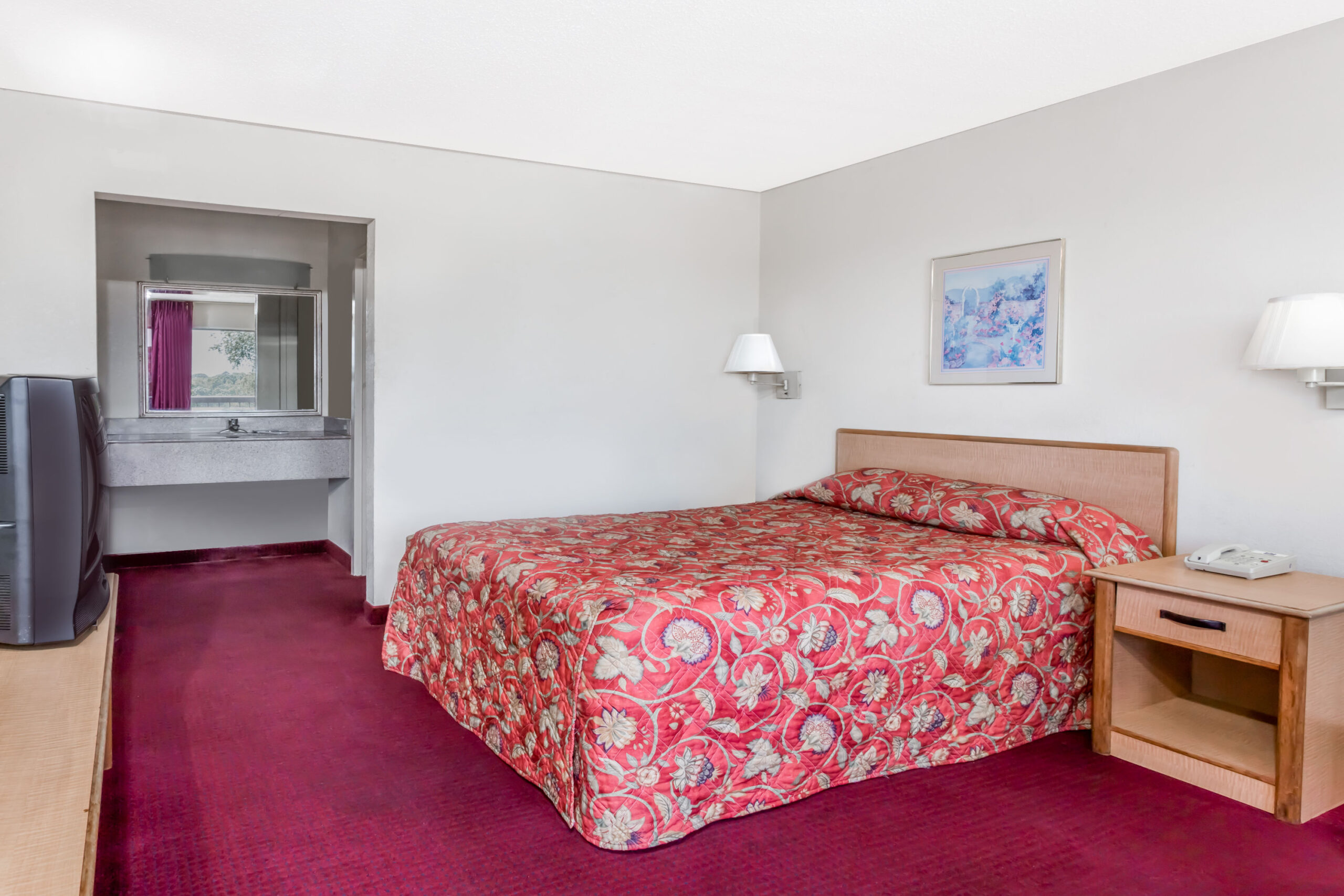 Hotel room with red patterned bedspread.