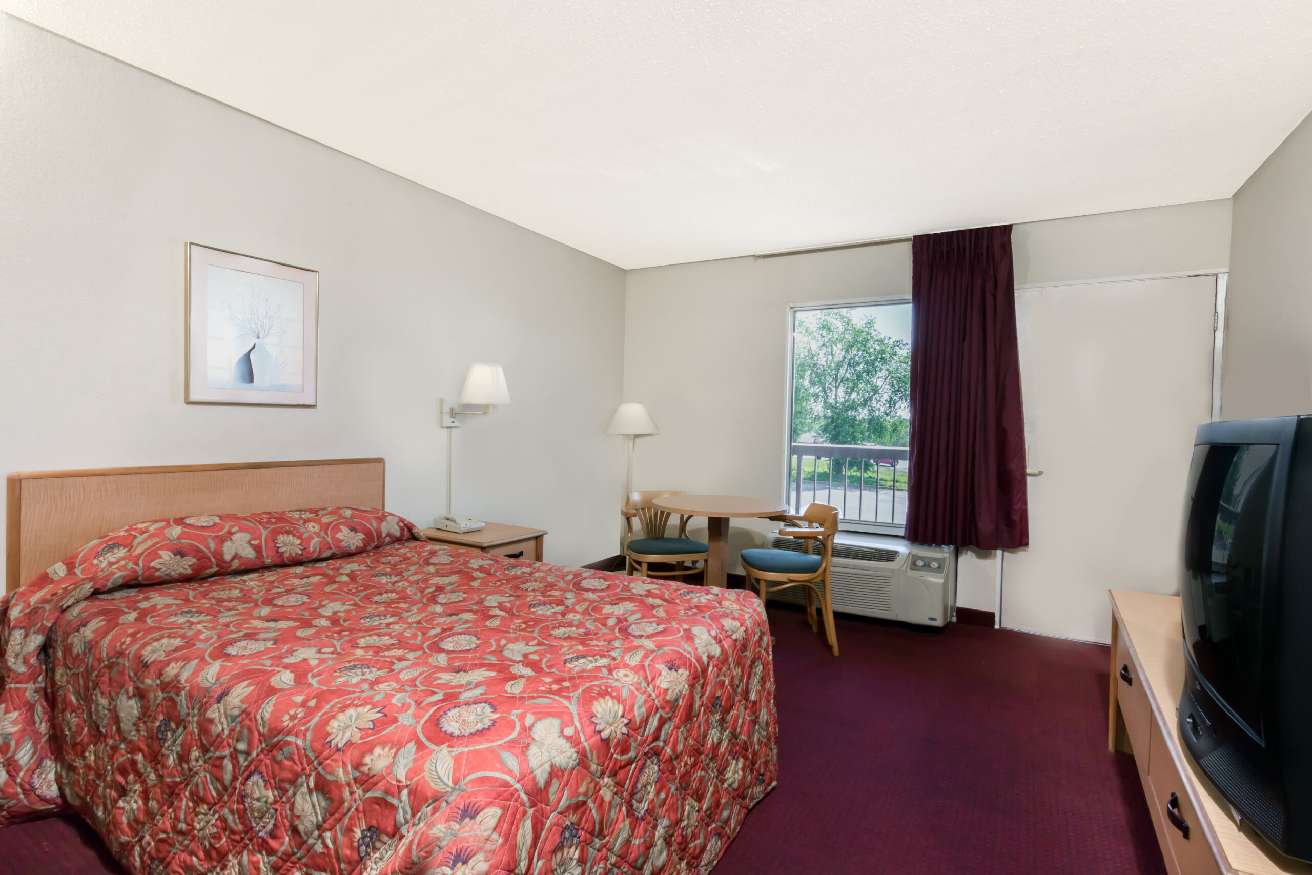 Hotel room with red patterned bedspread.