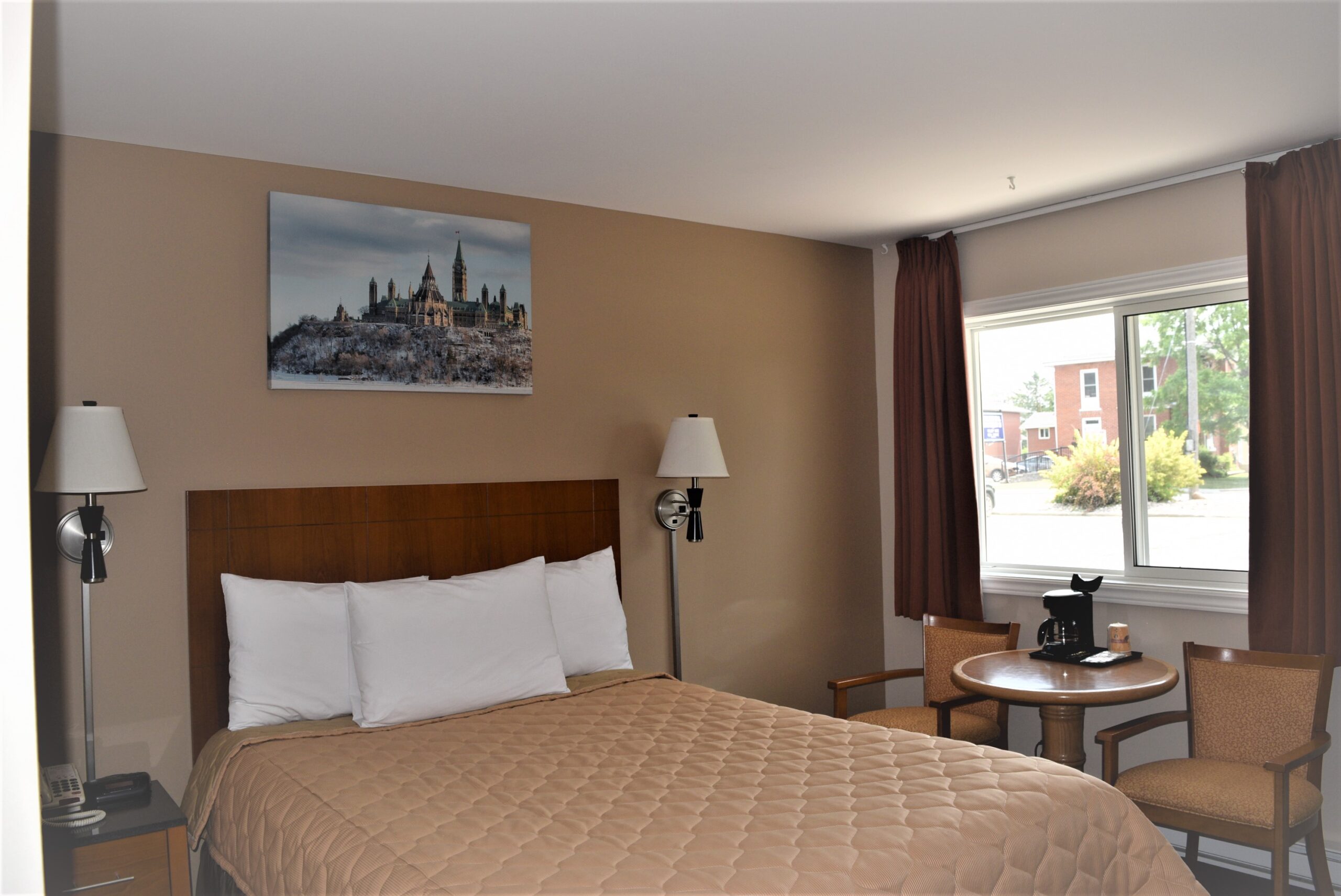 Hotel room with a queen bed and small dining area.