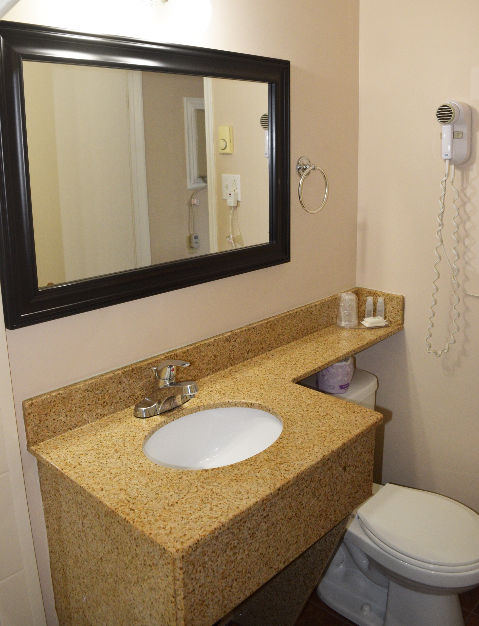 Hotel bathroom with a granite countertop sink.