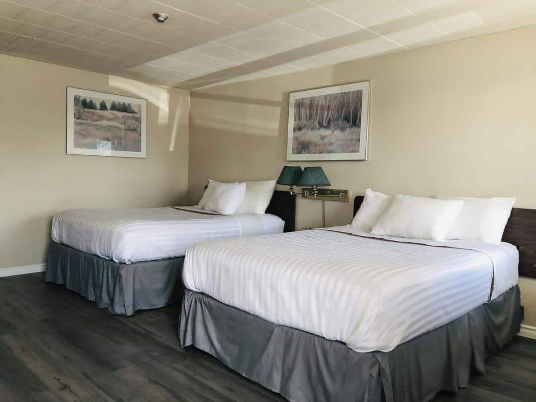 Hotel room with two double beds and framed art.
