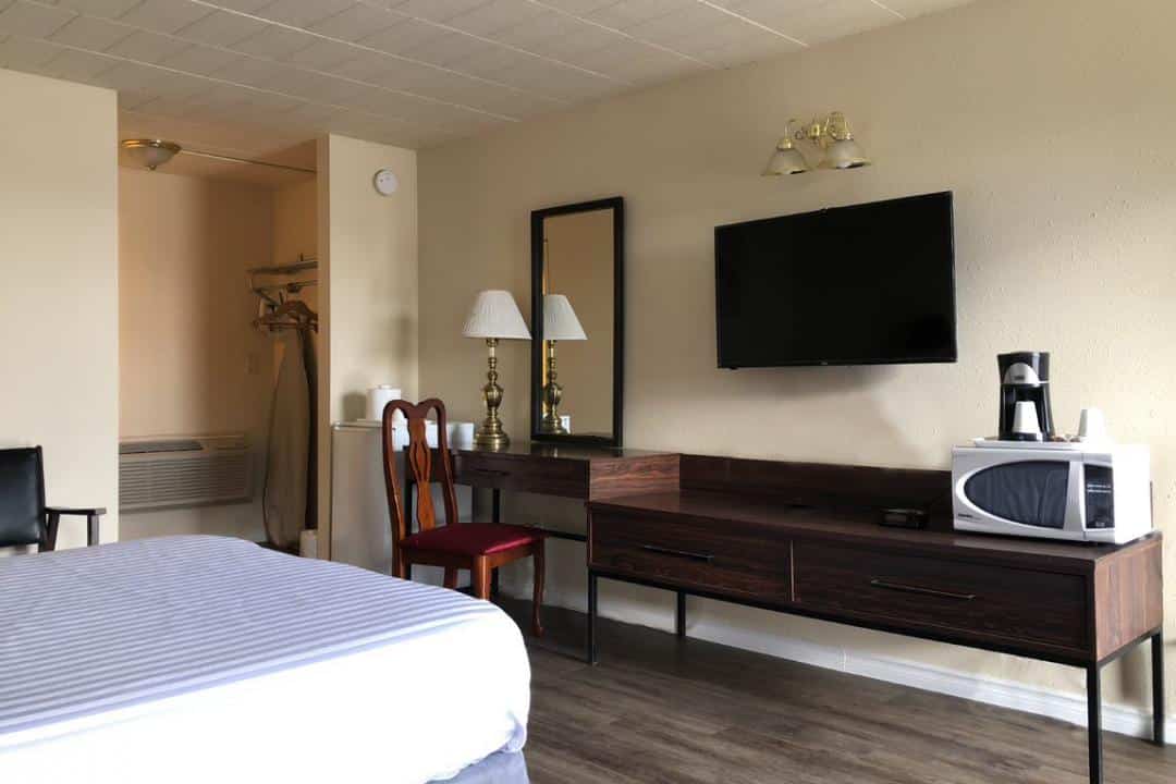 Hotel room with a bed, desk, and TV.