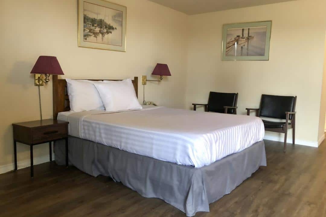 Hotel room with a queen bed and two chairs.