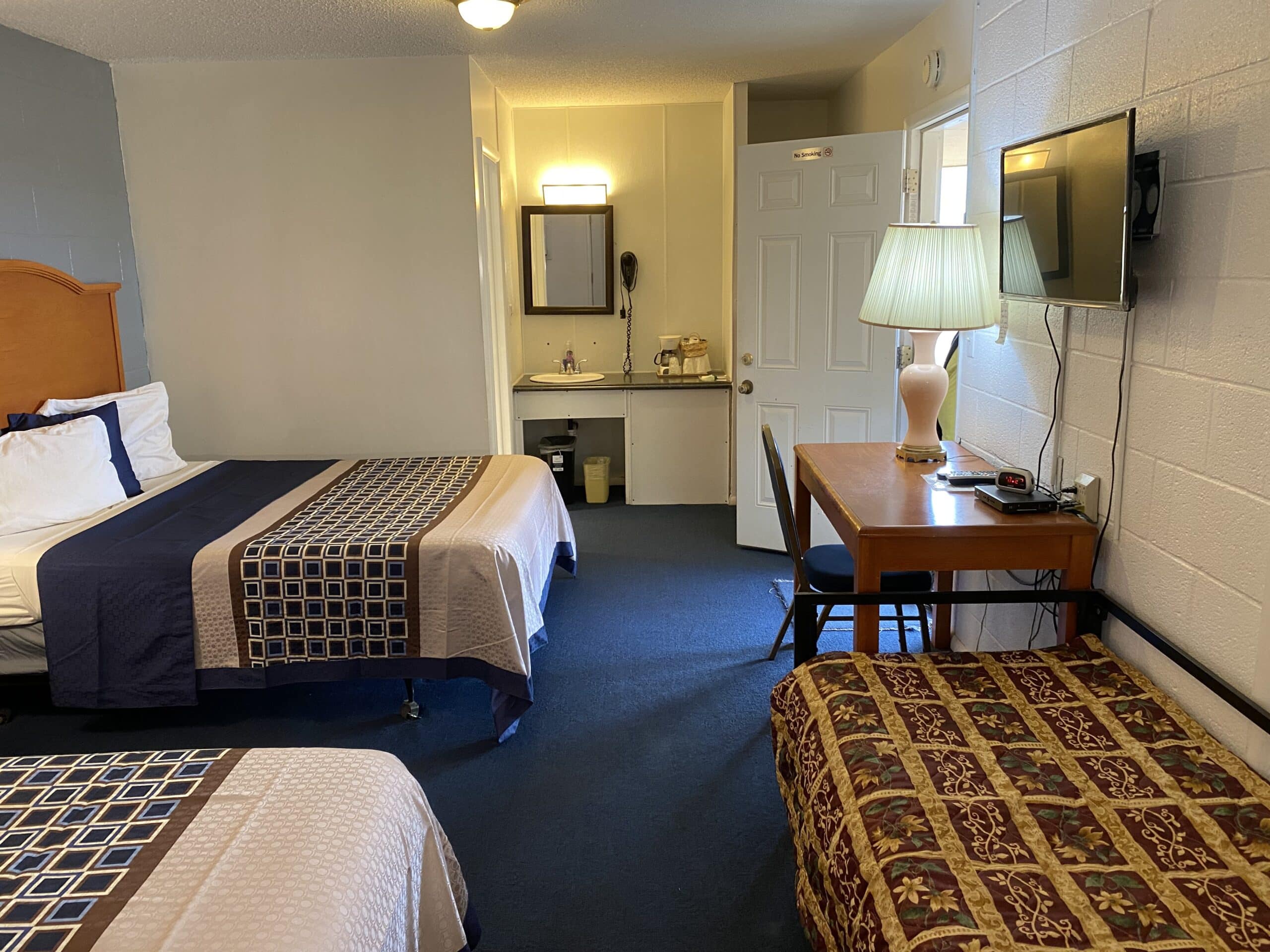 Hotel room with two beds and a working area.